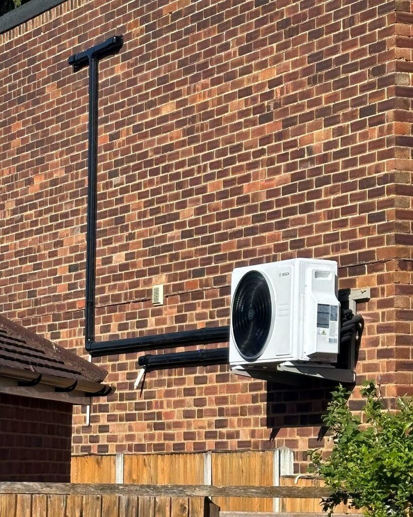 Bosch air conditioning outdoor unit on a wall bracket with neat black pipe trunking, installed by A.C. Wilgar